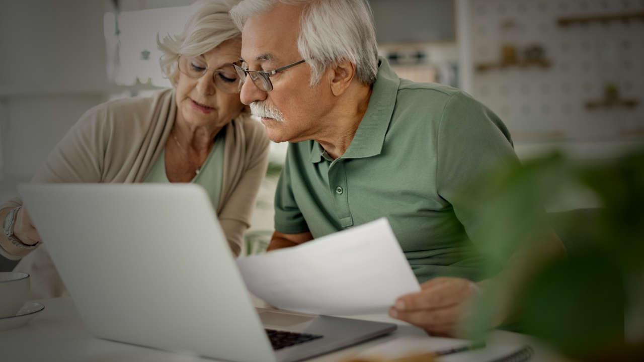Casal de aposentados conferindo o novo benefício exclusivo para idosos no notebook