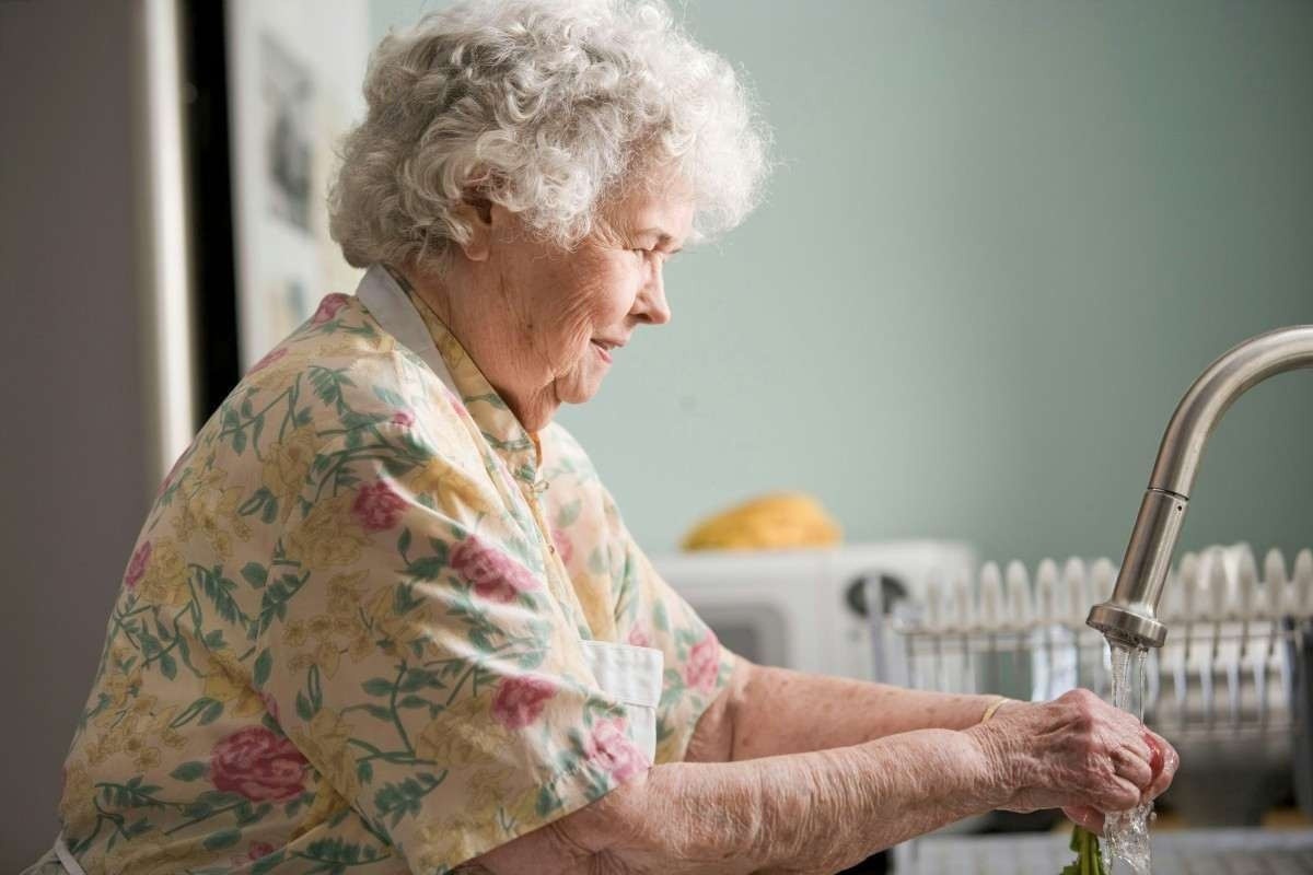 Senhora idosa lavando a louça