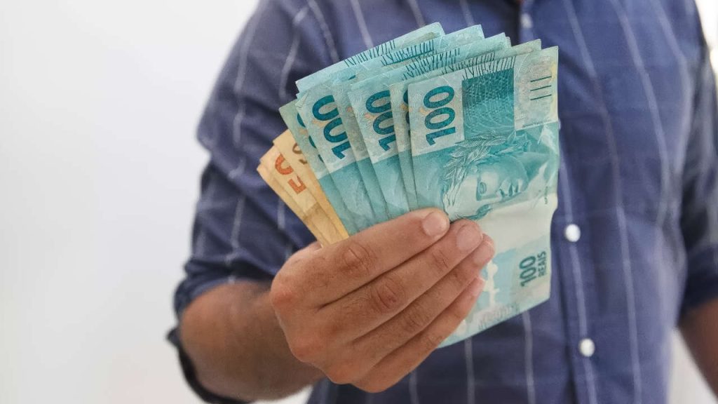 Pessoa segurando dinheiro que recebeu do novo programa do governo vai liberar até R$2.490
