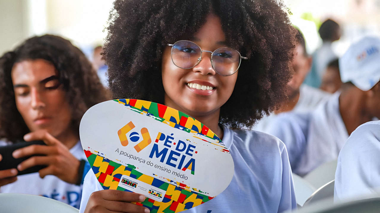 Estudante negra segurando placa do Pé-de-Meia