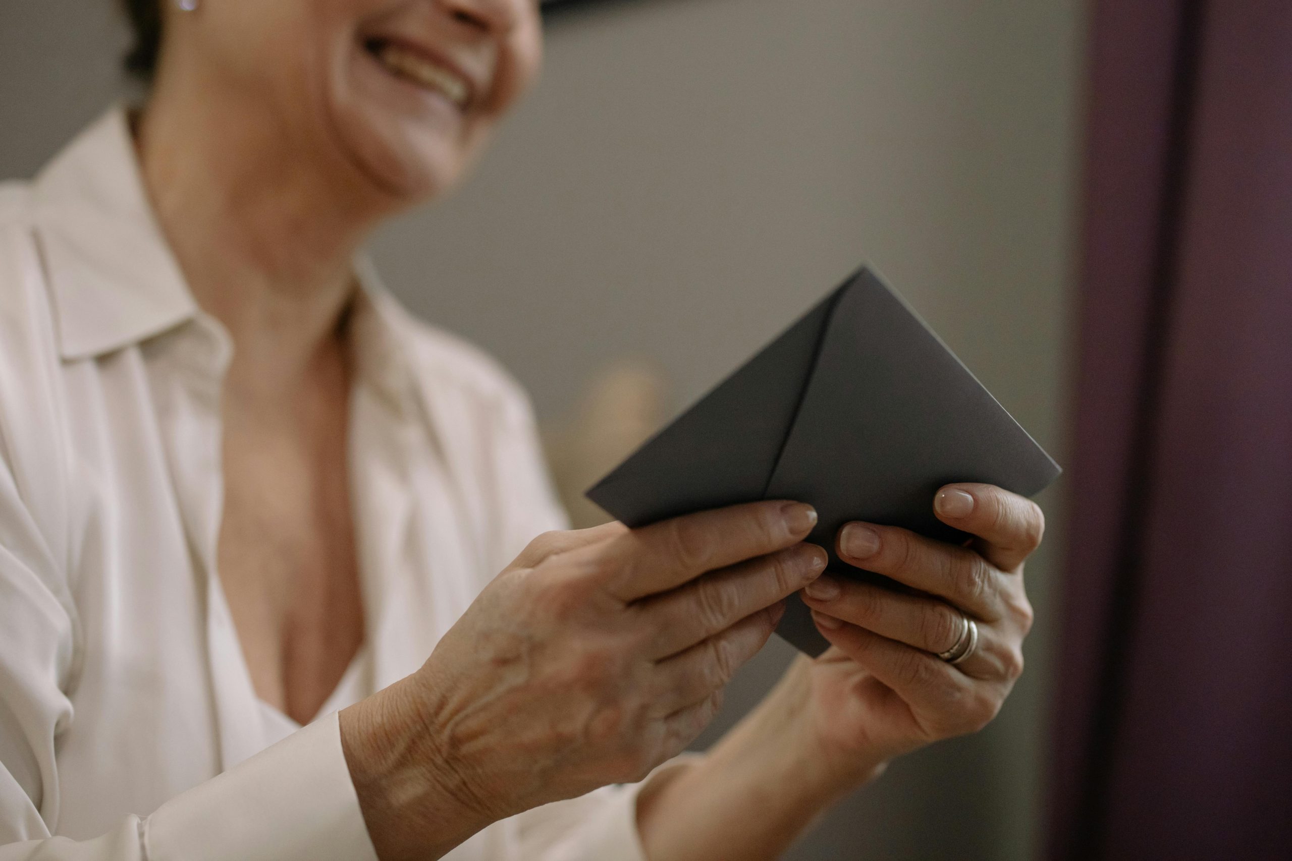 Uma mulher sorrindo com um envelope preto na mão após ver que o Governo faz alerta geral