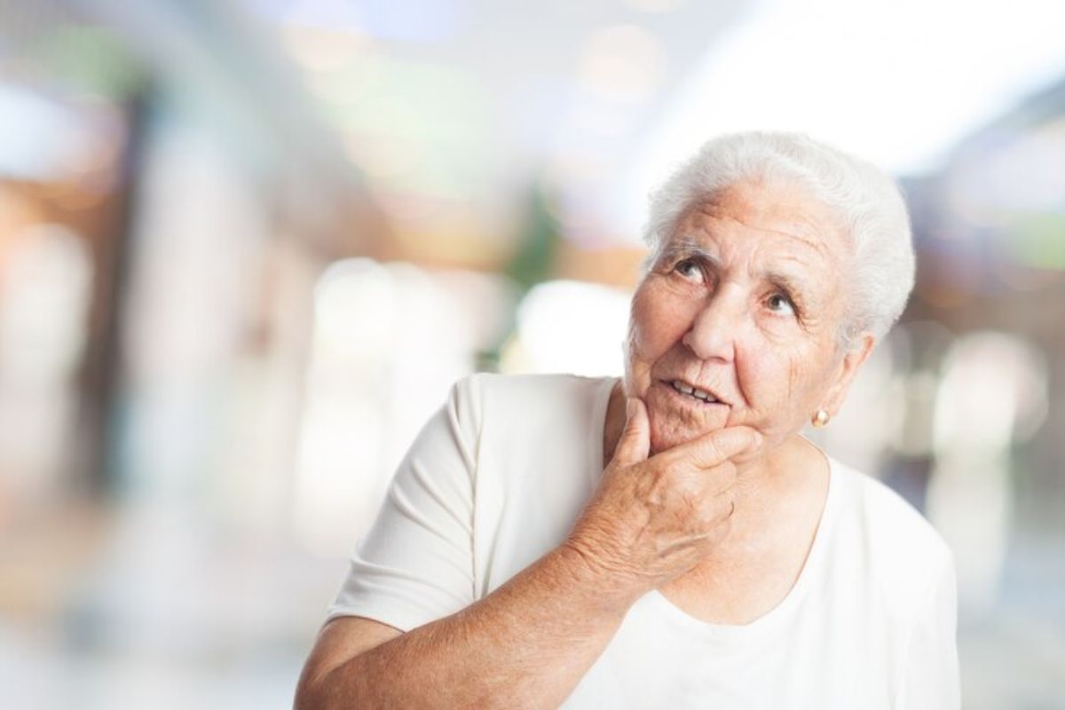 Uma idosa com a mão no queixo pensativa após ver a decisão do STF para os Aposentados do INSS