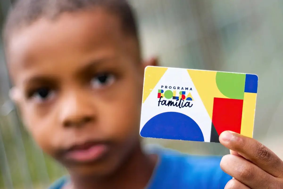 Uma criança segurando o cartão do Bolsa Família