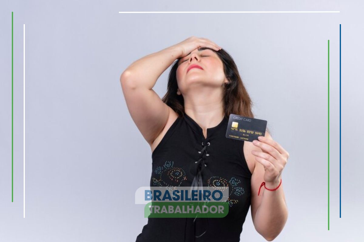 Uma mulher segura o cartão de crédito e leva a mão à cabeça após ver o comunicado da Serasa para negativados