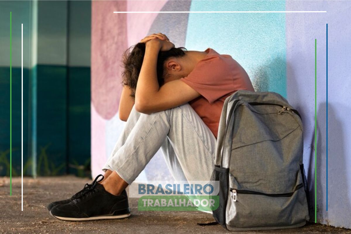 Jovem sentado triste encostado na parede por seu um nem-nem