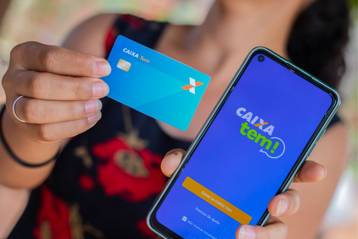 Uma mulher animada segura o seu cartão e smartphone com aplicativo após ver como receber R$ 200 a mais no Caixa Tem