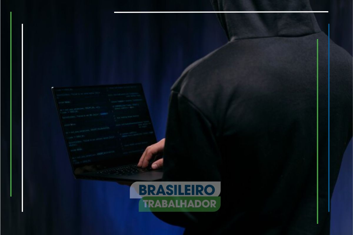 Um hacker com seu notebook na mão enquanto pratica o roubo de dados de cartões