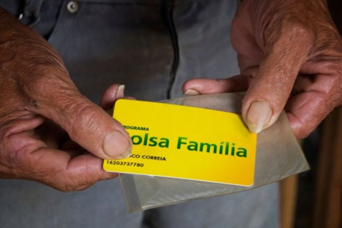 Uma pessoa triste segura o cartão do benefício após ver que o SEU BOLSA FAMÍLIA foi reduzido