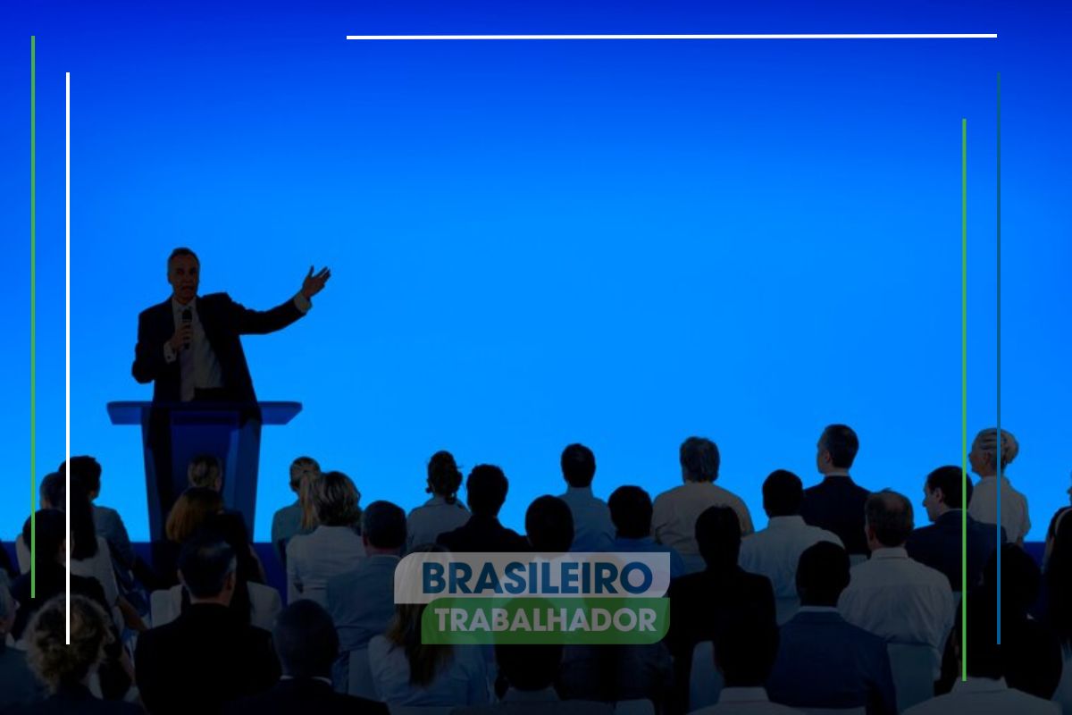 Um homem em um palco ensina para uma plateia Como Falar em Público