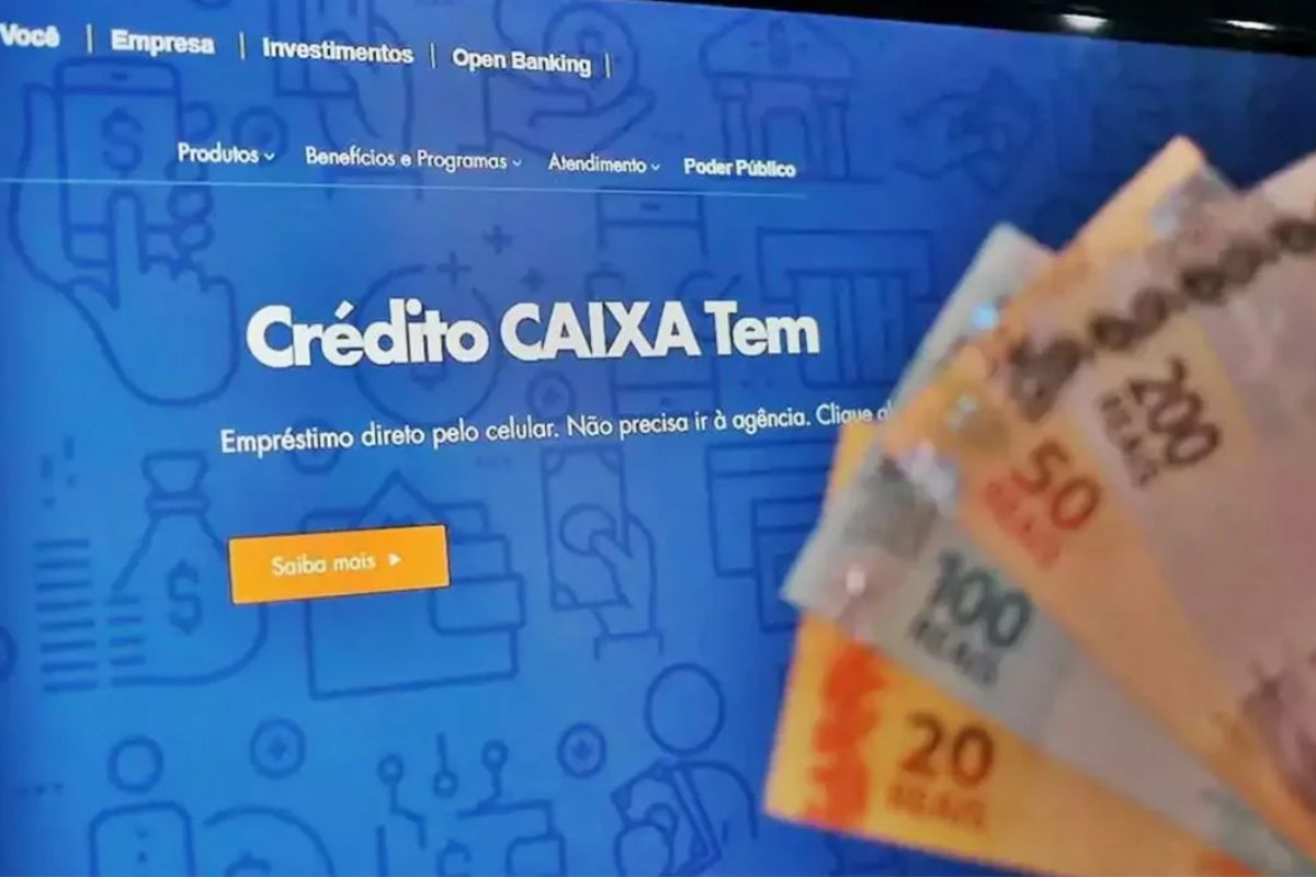 Algumas notas de reais frente a um computador no site da Caixa. A pessoa faz a solicitação do Empréstimo no Caixa Tem liberado para idosos 