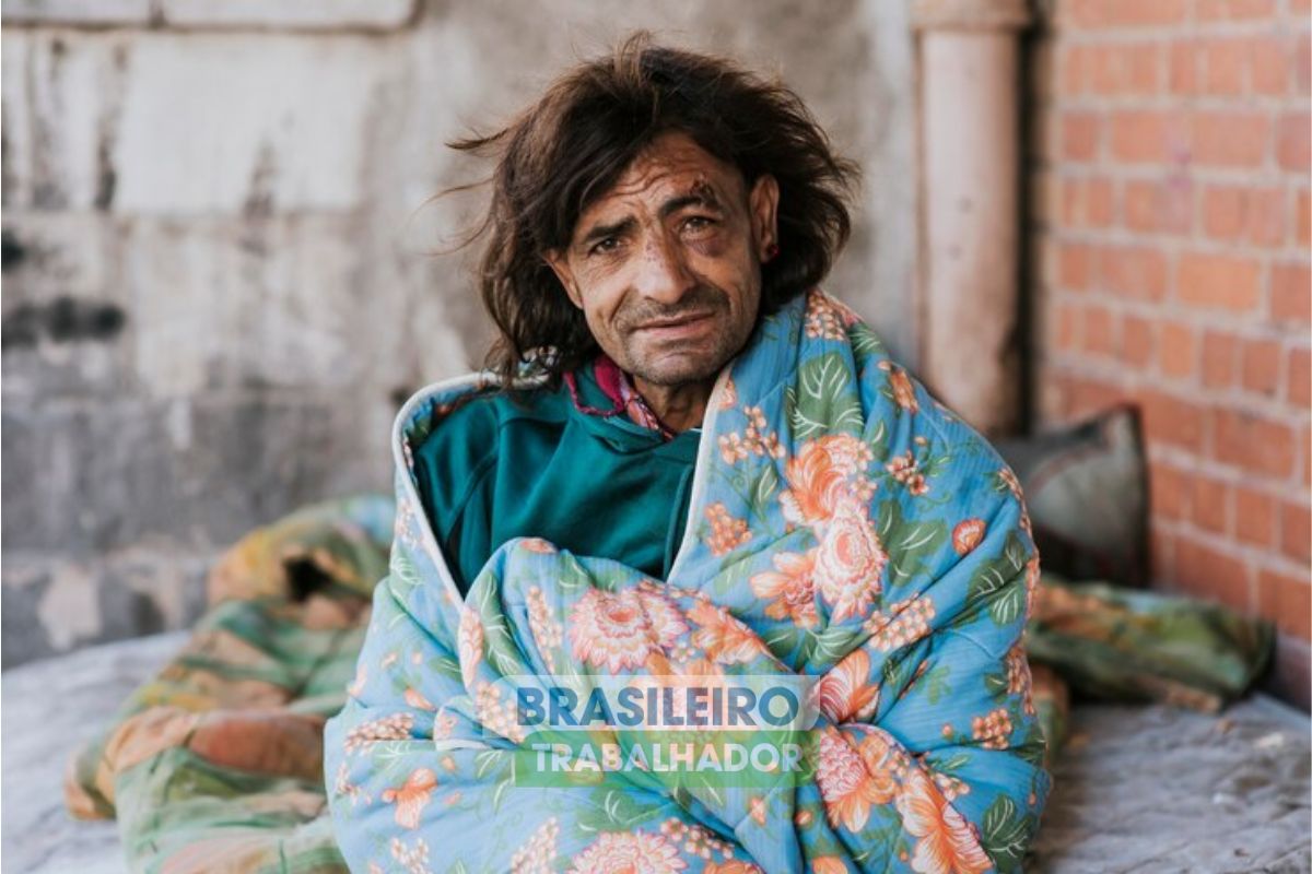 Um senhor de rua sentado em sua cama na Moradia precária em que vive