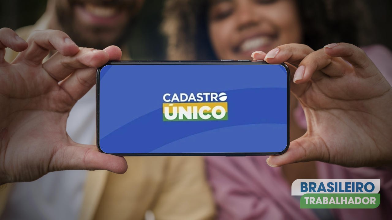 Casal sorridente segurando smartphone com aplicativo do CadÚnico