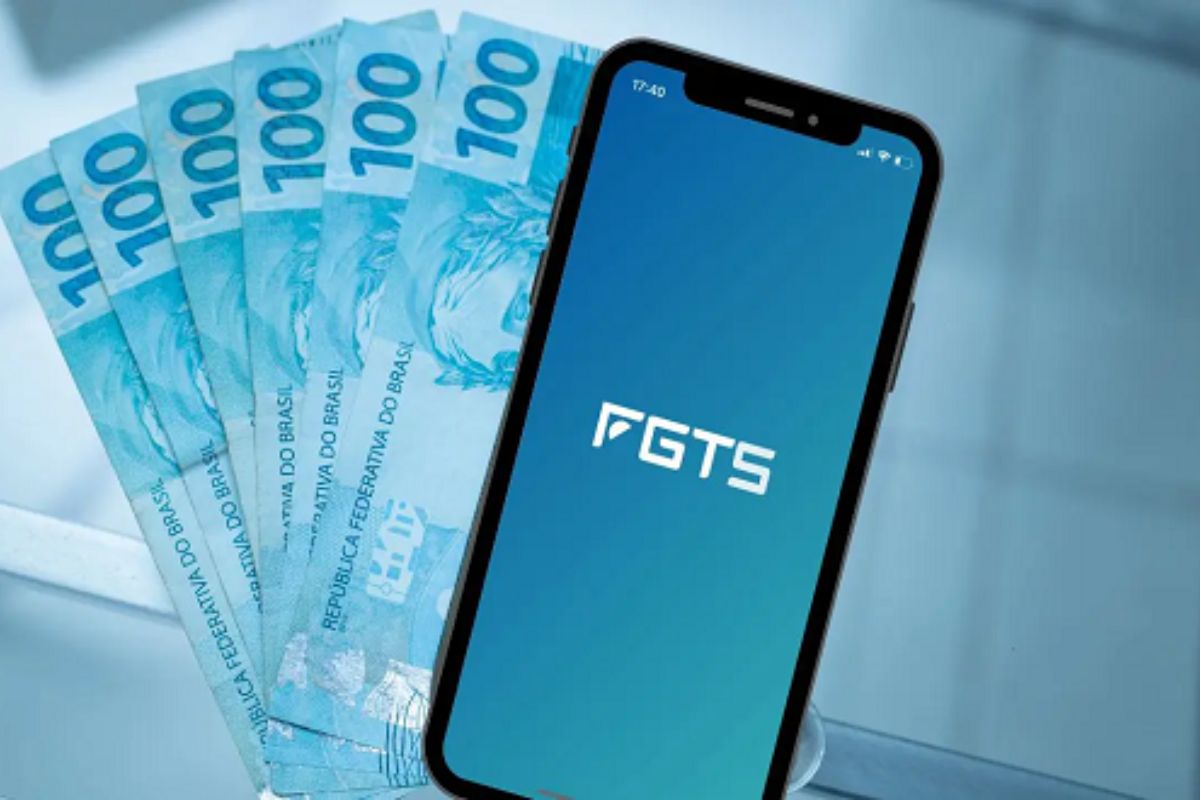 Um aplicativo do FGTS em um celular em cima de notas mostrando que não houve o Fim da multa de 40% do FGTS está próximo