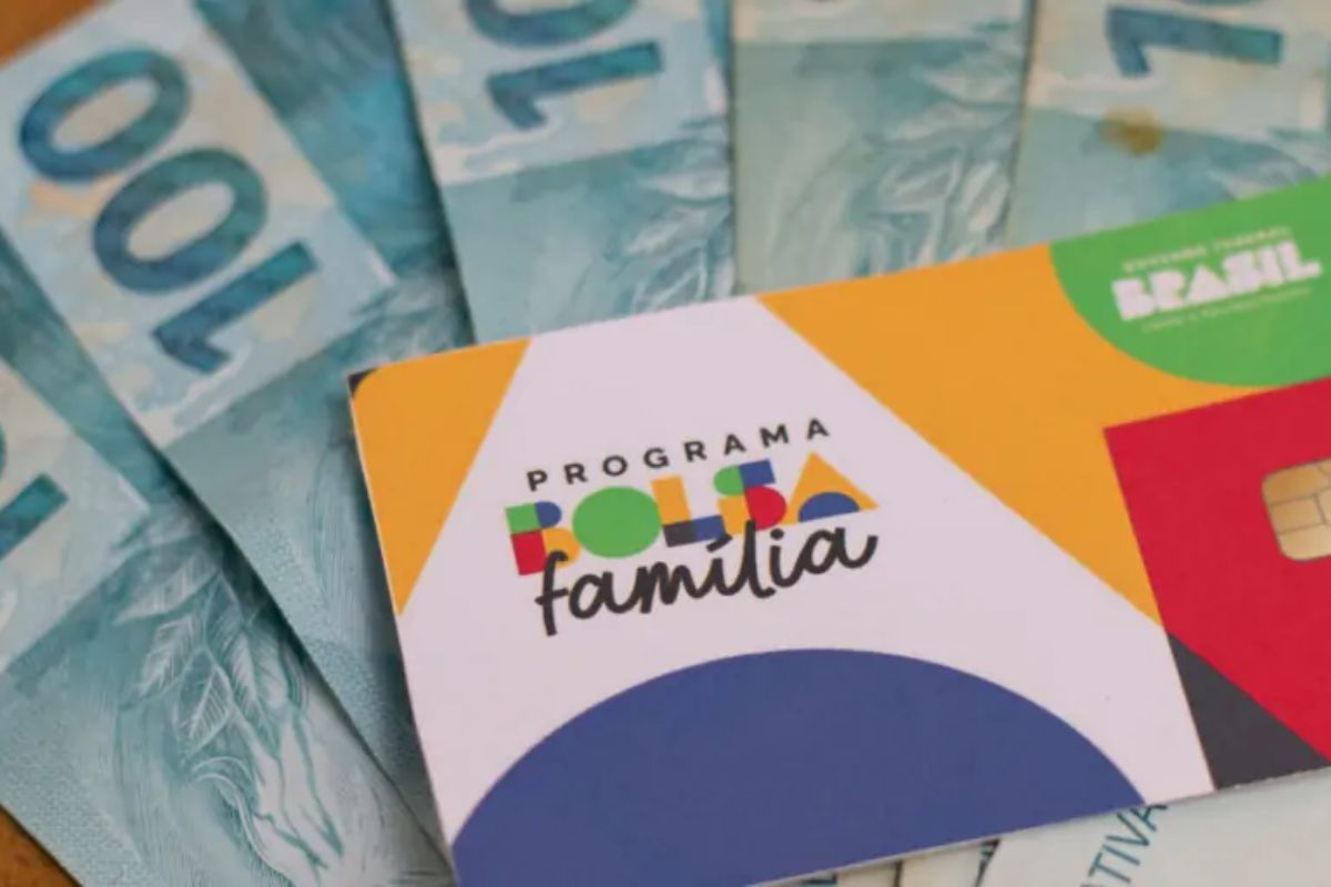 Um cartão do benefício do Bolsa Família em cima de algumas notas de 100 reais representando que o Pagamento do auxílio gás chega mais cedo neste mês