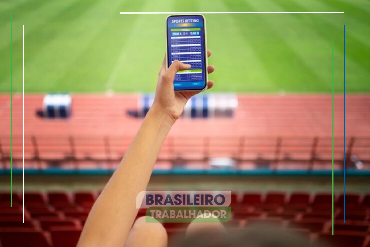 Uma pessoa na arquibancada acessando um app de bet no smartphone após ver que Sites de apostas serão bloqueados