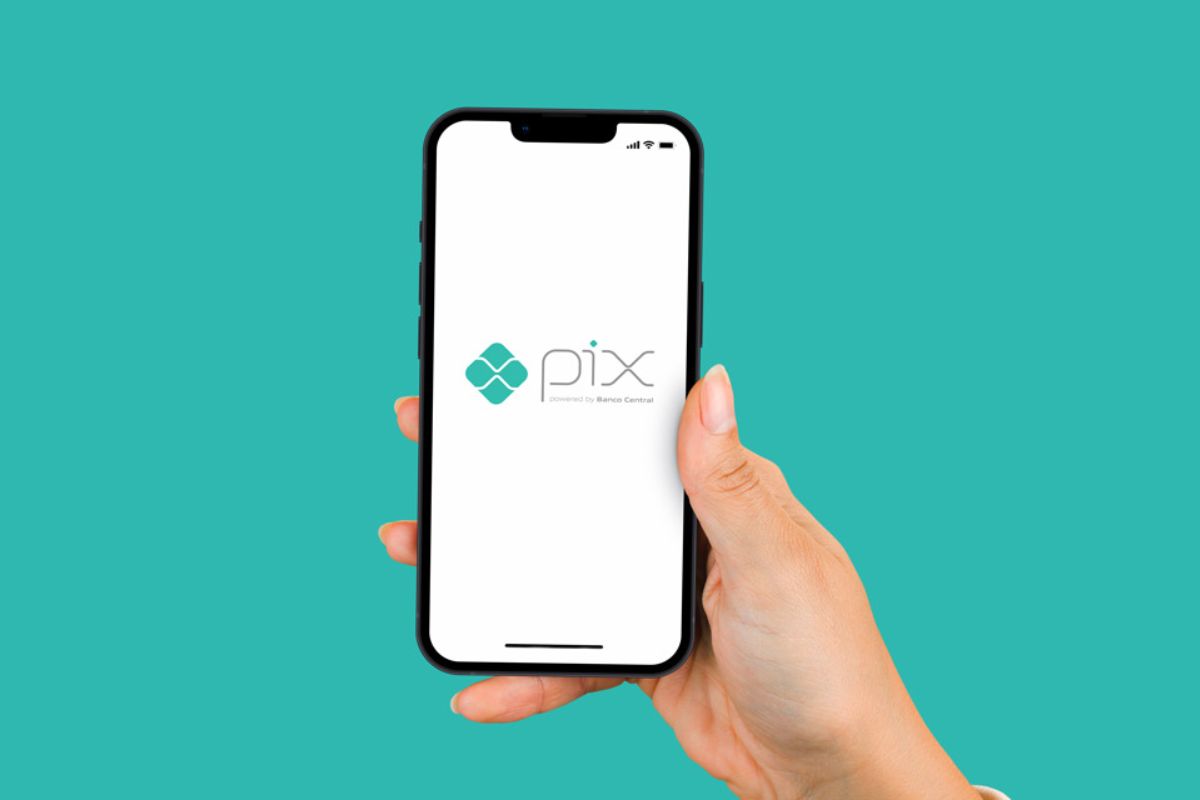 Uma mão segurando um aplicativo com a imagem do PIX, destacando que o PIX agendado será obrigatório