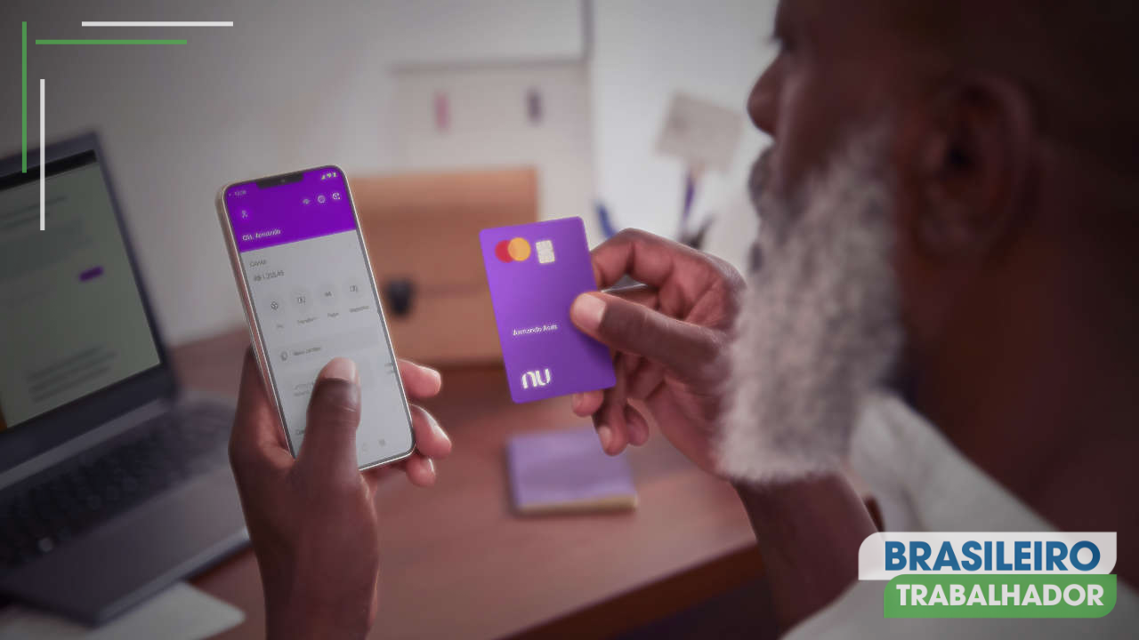 Homem consultando aplicativo Nubank no celular e segurando cartão de crédito