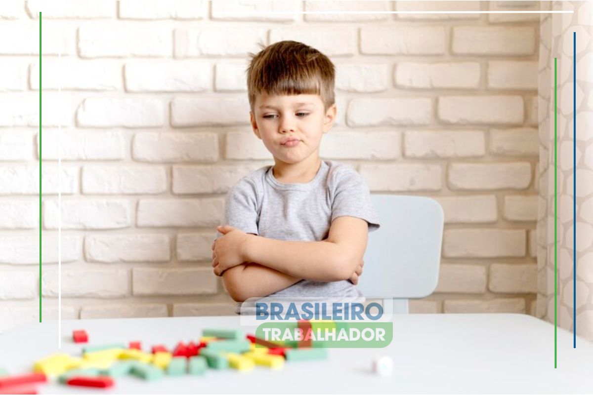 Uma criança sentada em uma mesa onde há alguns brinquedos. Ela passa pelas novas regras para a educação de pessoas com autismo