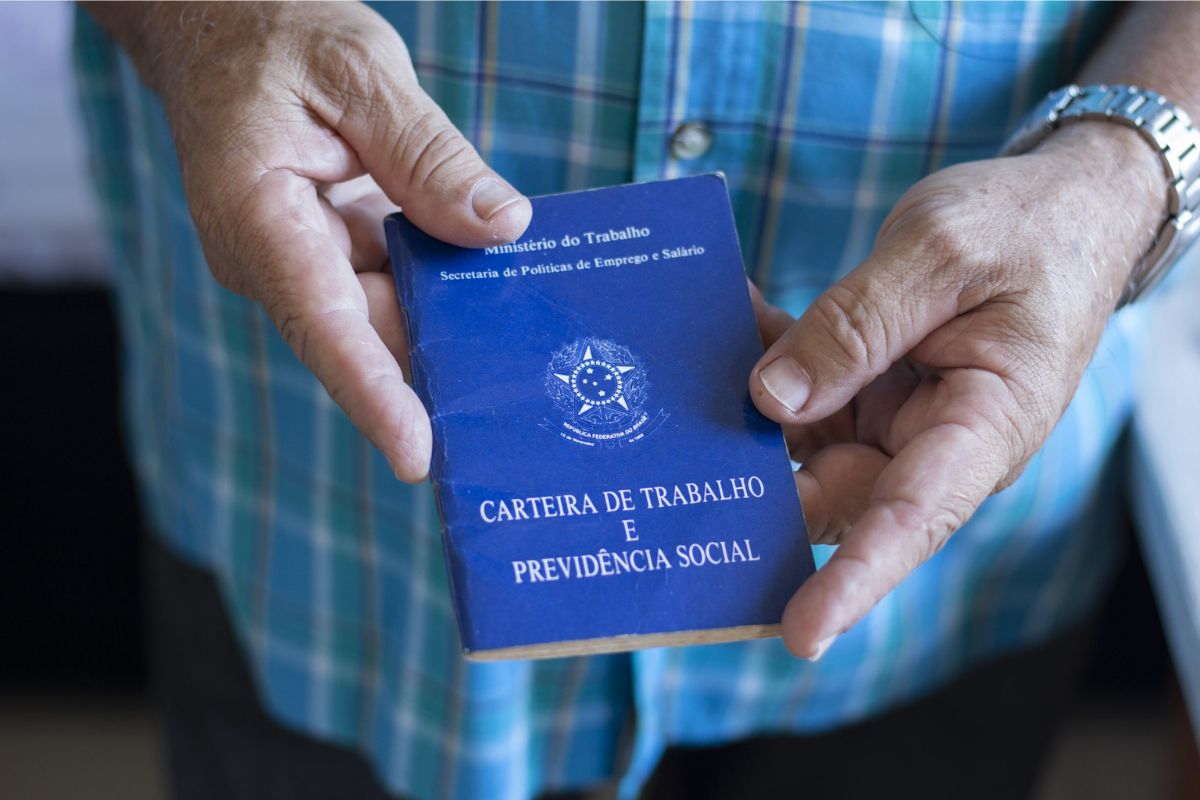 Um homem segurando sua carteira de trabalho depois de viver anos sem carteira de trabalho