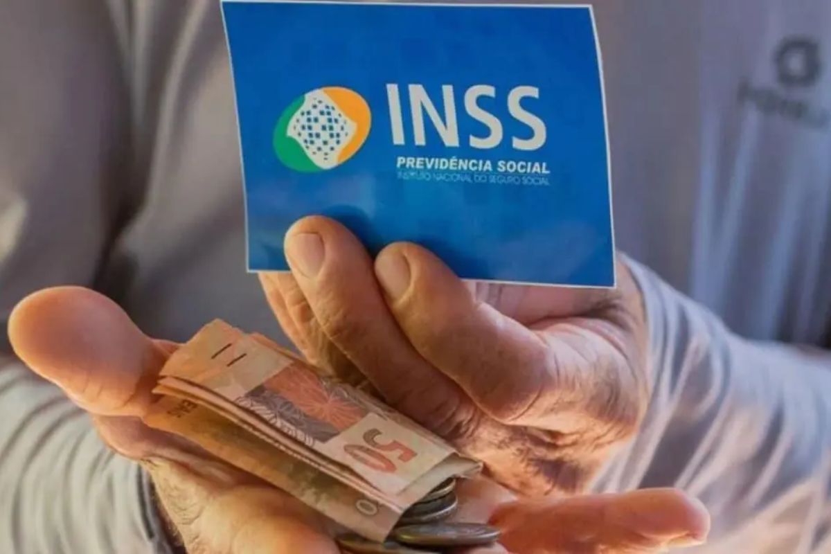 Um homem segura o cartão do benefício e o dinheiro que recebeu após ver o calendário 13º salário do INSS em 2024