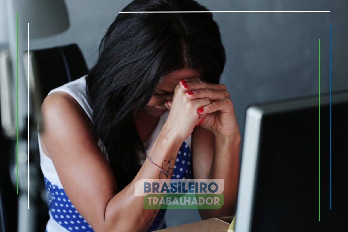 Uma mulher preocupada em frente ao computador pensando no caso de assédio moral no trabalho