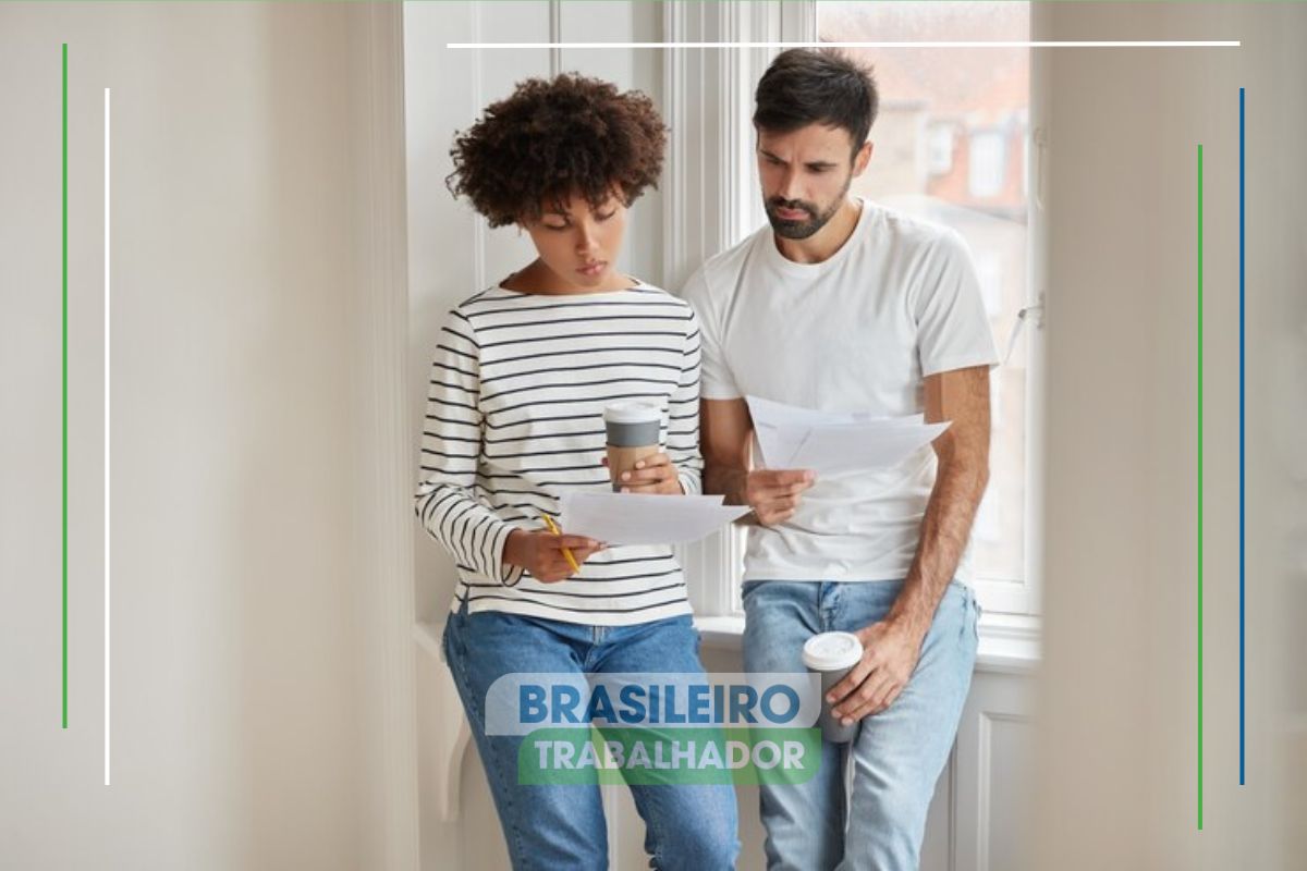 Um casal na sala da casa lendo os documentos para aprovação do Crédito imobiliário em 2025