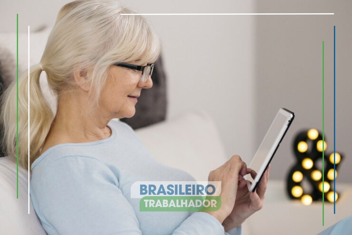 Uma mulher sentada em seu sofá fazendo a Prova de vida INSS 2025 pelo tablet