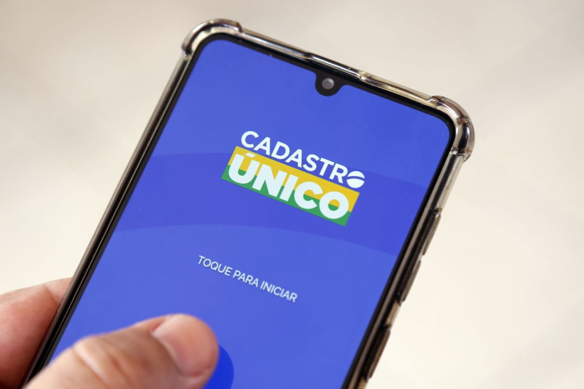 Uma pessoa com o celular na mão abrindo o app do CadÚnico