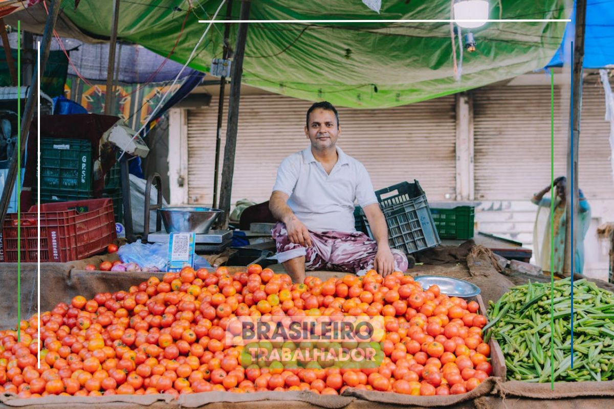 Um rapaz em sua banca de tomate, sentado ele parece triste com a Inflação na feira