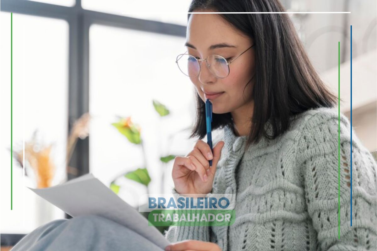 Uma mulher com caderno na mão e caneta na boca, ela vê que Mulheres dominam bolsas de mestrado e doutorado