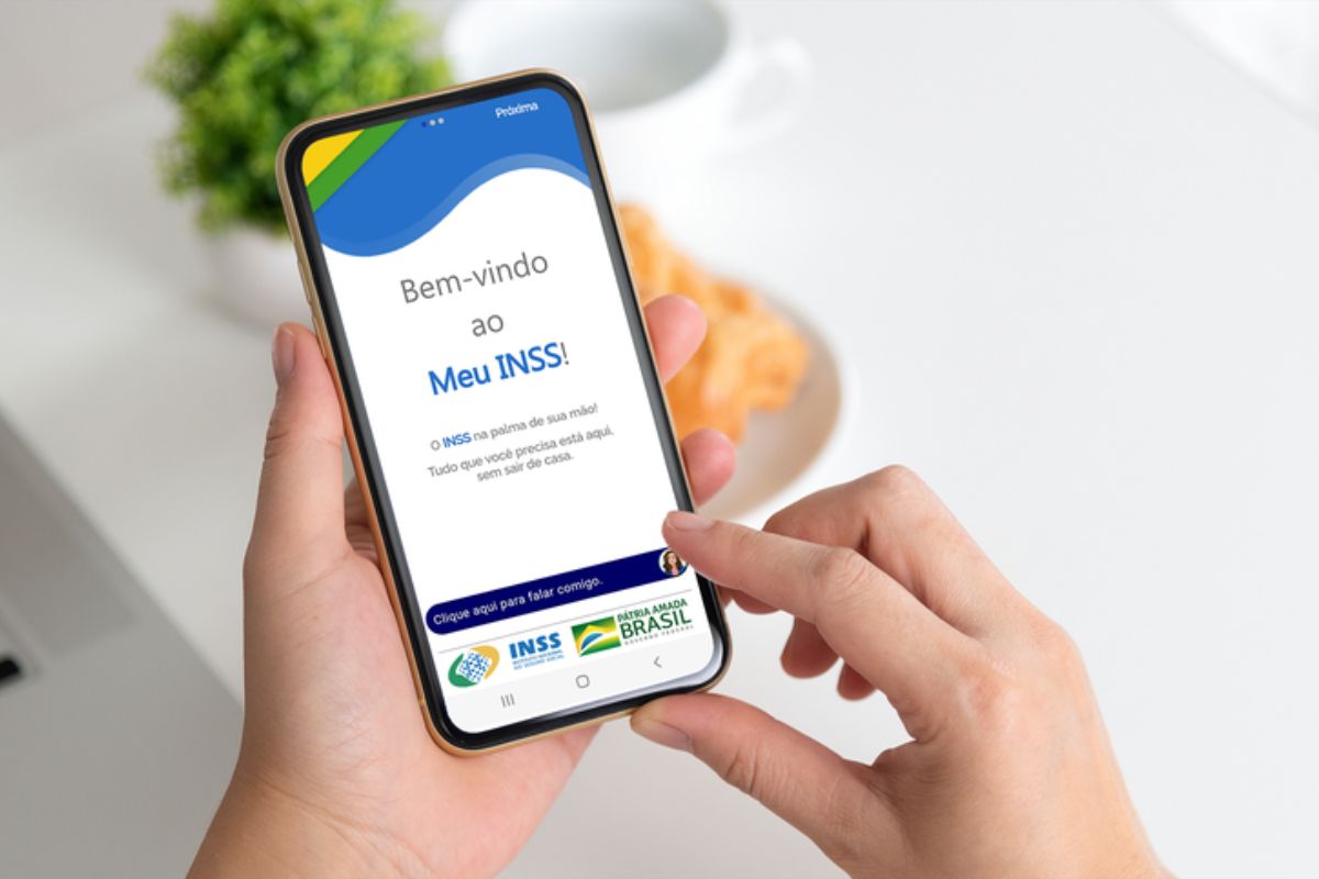 O smartphone está na mão de uma pessoa com a tela da Nova Versão do Meu INSS