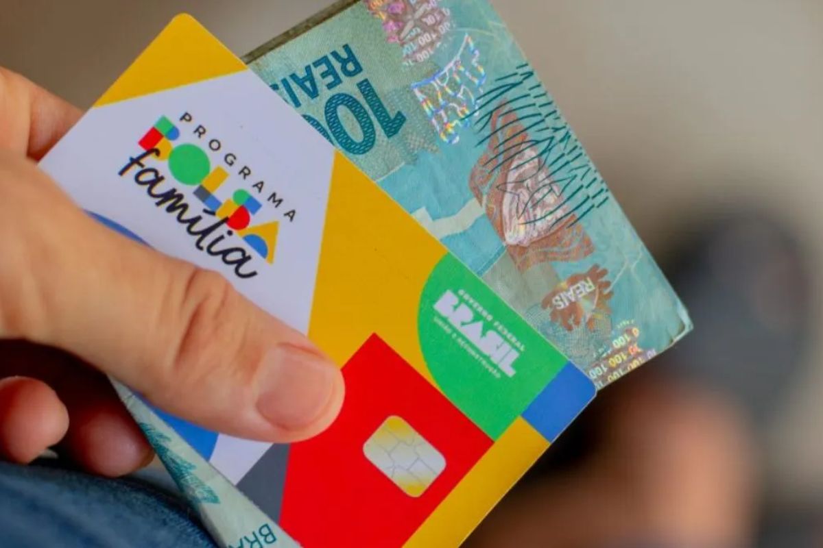 Uma pessoa com o cartão e o valor do Bolsa Família em maio na mão